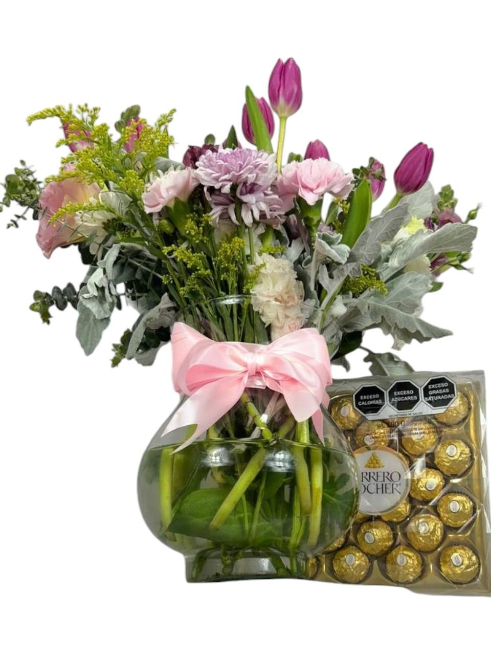 Arreglo Floral de Tulipanes con Ferrero | Tulipanes Radiante 5 Jarrón de vidrio con tulipanes morados, claveles y crisantemos pastel, follaje gris y lazo rosa, con caja de chocolates Ferrero Rocher.