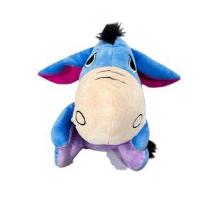 Peluche de burro azul con hocico beige, orejas rosa, crin negra y patas lila; tela afelpada.