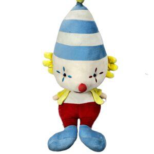 Peluche de payaso con gorro cónico azul a rayas, nariz roja, chaleco amarillo, pantalón rojo y zapatos azules.
